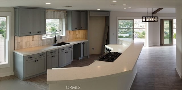 kitchen with pendant lighting, backsplash, gray cabinetry, and sink