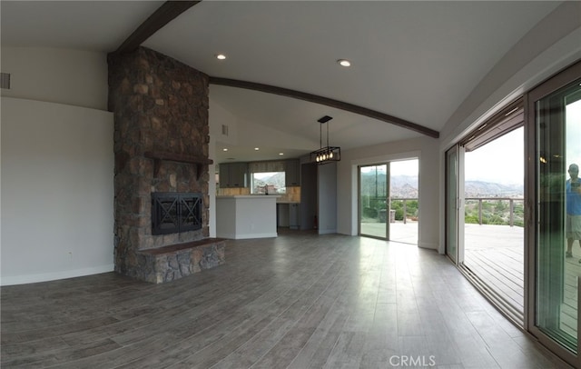 unfurnished living room with a stone fireplace, lofted ceiling with beams, and hardwood / wood-style floors