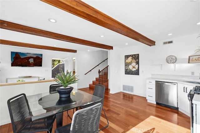 dining space with beam ceiling, sink, and light hardwood / wood-style flooring