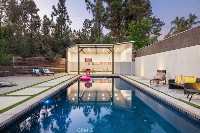 pool at dusk featuring a patio area