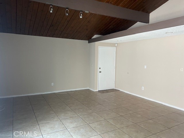 tiled spare room featuring vaulted ceiling with beams and wooden ceiling