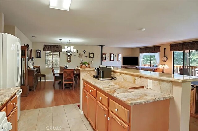 kitchen featuring light stone countertops, a center island, light hardwood / wood-style flooring, and a chandelier