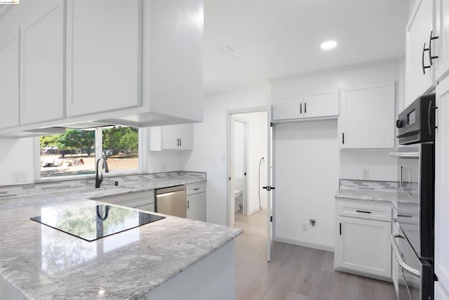 kitchen with light stone counters, light hardwood / wood-style flooring, white cabinets, and stainless steel dishwasher