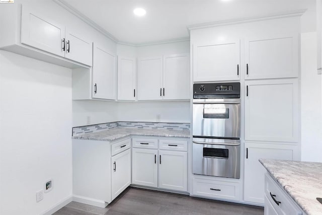 kitchen with light stone countertops, dark hardwood / wood-style flooring, ornamental molding, double oven, and white cabinets