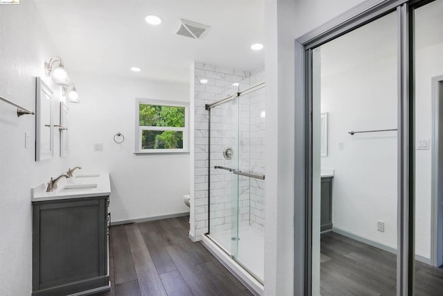 bathroom with hardwood / wood-style floors, vanity, toilet, and a shower with door