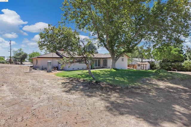 view of front of house with a front lawn and a storage shed