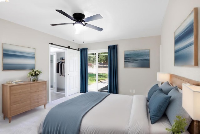 carpeted bedroom featuring a walk in closet, a barn door, a closet, and ceiling fan