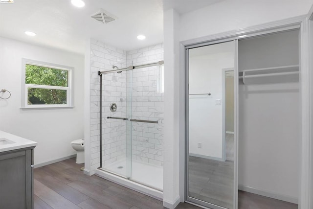 bathroom with wood-type flooring, vanity, toilet, and walk in shower