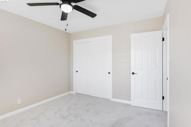 unfurnished bedroom with ceiling fan, light carpet, and a closet