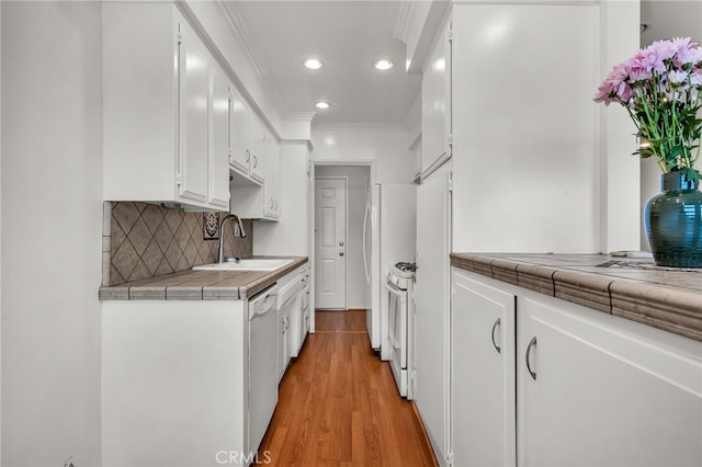 kitchen with white cabinets, white appliances, light hardwood / wood-style flooring, tile counters, and sink