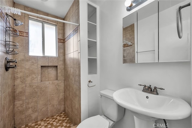 bathroom with sink, toilet, and tiled shower