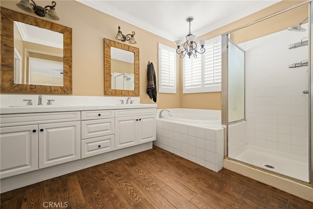 bathroom featuring plus walk in shower, an inviting chandelier, hardwood / wood-style floors, crown molding, and vanity