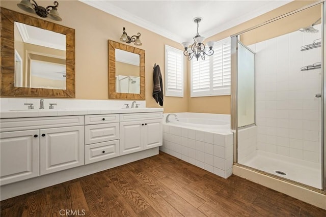 full bath with wood finished floors, a sink, a notable chandelier, and crown molding