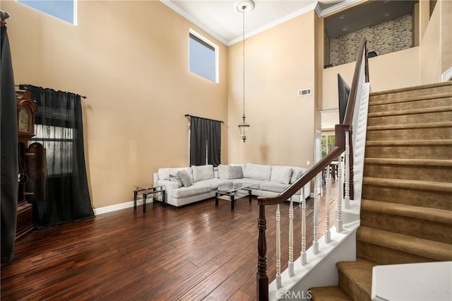 stairway featuring visible vents, hardwood / wood-style flooring, ornamental molding, and a high ceiling