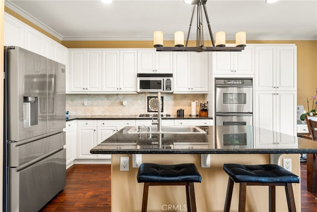 kitchen with white cabinetry, an island with sink, stainless steel appliances, crown molding, and dark hardwood / wood-style floors