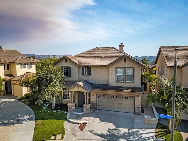 view of front of home featuring stucco siding, driveway, stone siding, a mountain view, and a garage