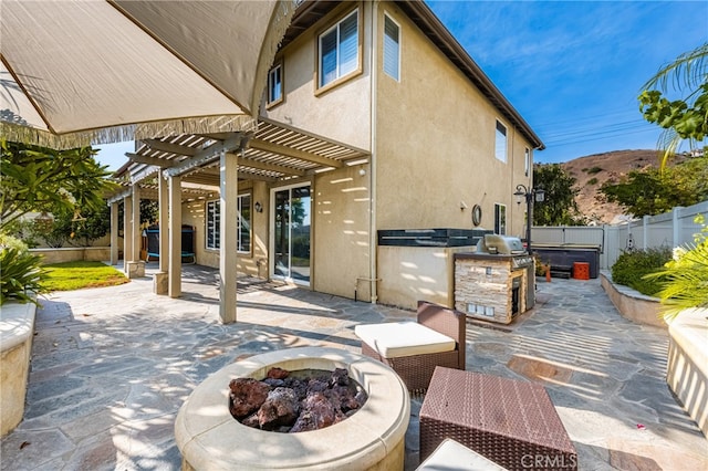 view of patio with a pergola, a fire pit, a mountain view, and an outdoor kitchen