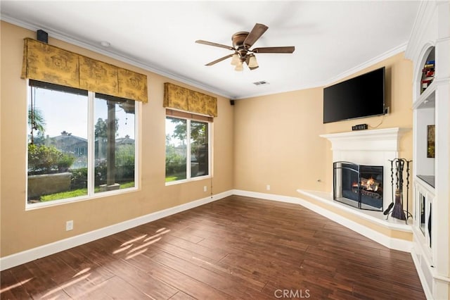 unfurnished living room with baseboards, a ceiling fan, a warm lit fireplace, crown molding, and hardwood / wood-style flooring