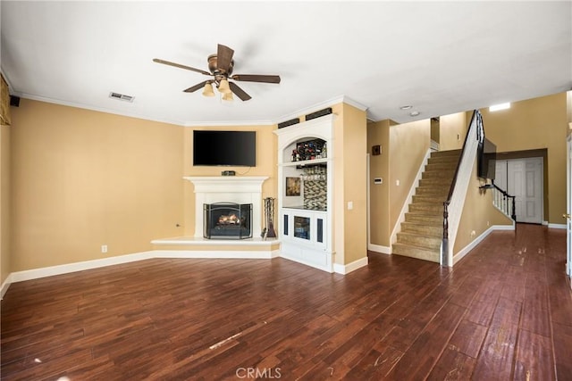 unfurnished living room with stairway, wood finished floors, visible vents, a lit fireplace, and ceiling fan