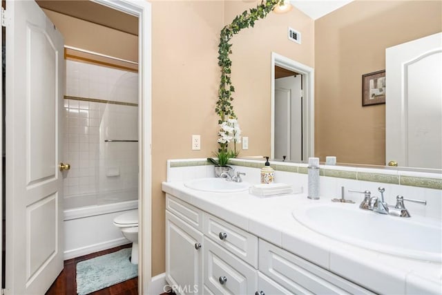 bathroom with visible vents, a sink, double vanity, and toilet