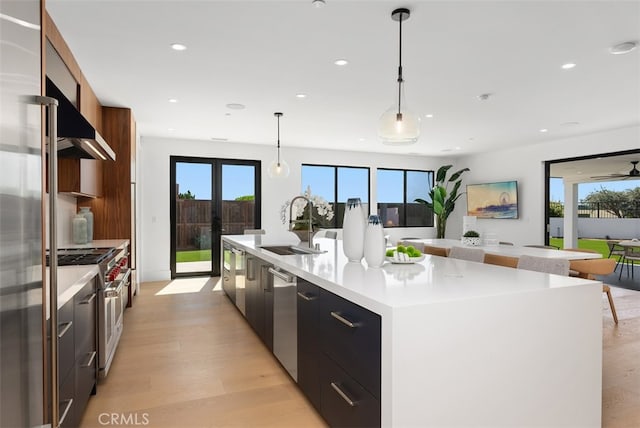 kitchen with a healthy amount of sunlight, a large island, stainless steel appliances, and decorative light fixtures