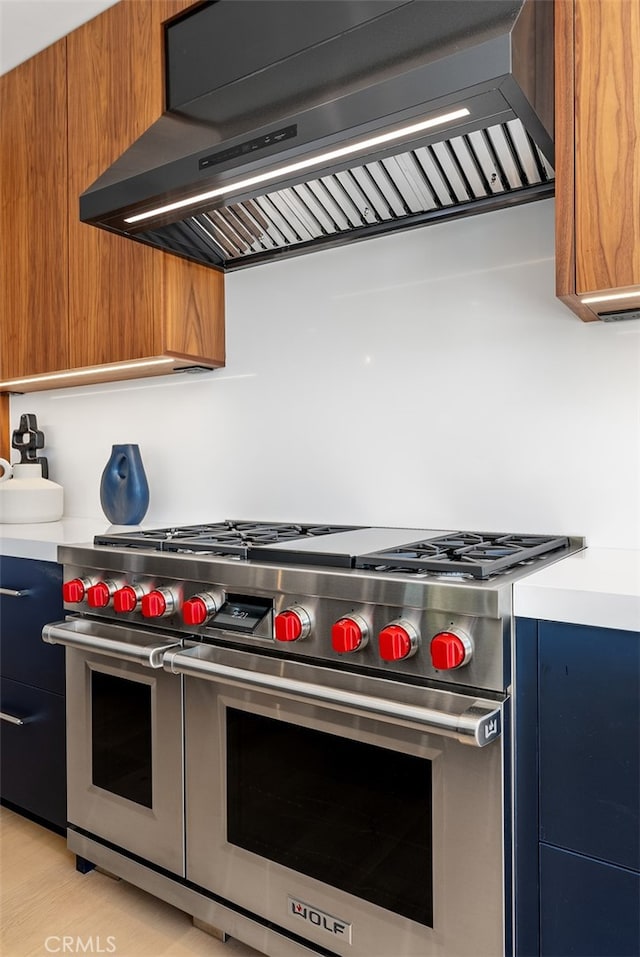 kitchen with light wood-type flooring, exhaust hood, and double oven range