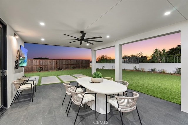 patio terrace at dusk with a yard and ceiling fan