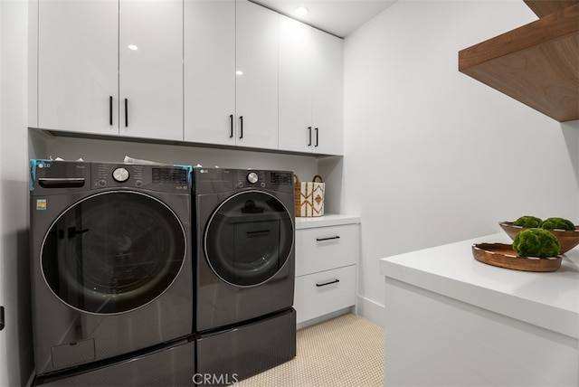 clothes washing area with cabinets and washer and dryer