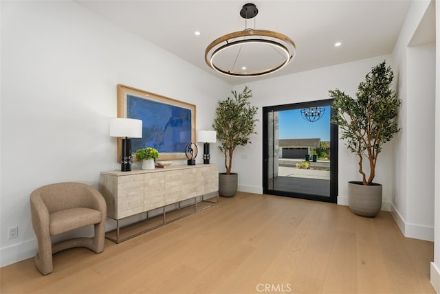 sitting room with an inviting chandelier and hardwood / wood-style flooring