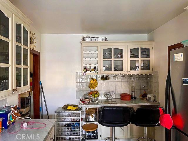 kitchen with decorative backsplash, stainless steel fridge, and a breakfast bar