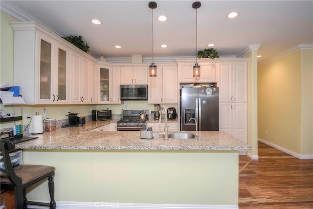 kitchen featuring kitchen peninsula, pendant lighting, stainless steel appliances, light wood-type flooring, and sink