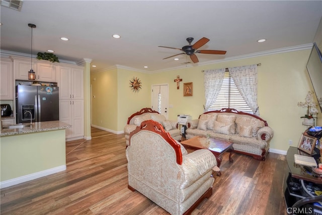 living room with ornamental molding, wood-type flooring, and sink