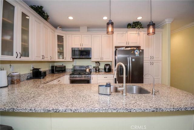 kitchen with pendant lighting, kitchen peninsula, white cabinetry, appliances with stainless steel finishes, and crown molding