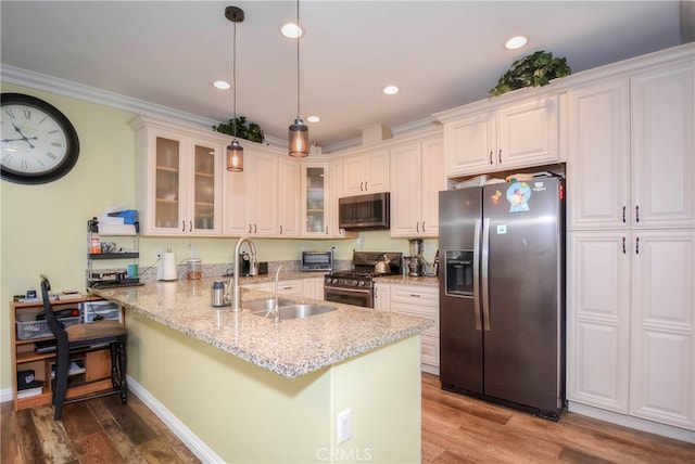 kitchen featuring hanging light fixtures, sink, appliances with stainless steel finishes, a breakfast bar, and hardwood / wood-style floors