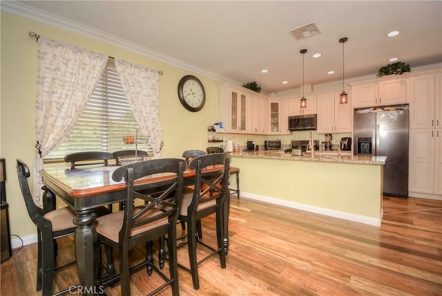 dining space with light hardwood / wood-style flooring and ornamental molding