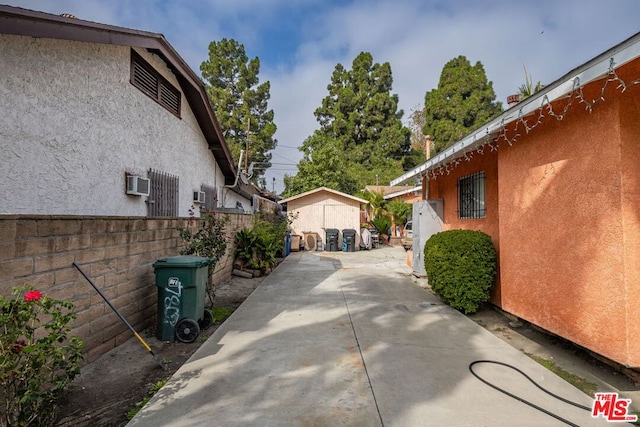 view of side of property with a patio and an AC wall unit