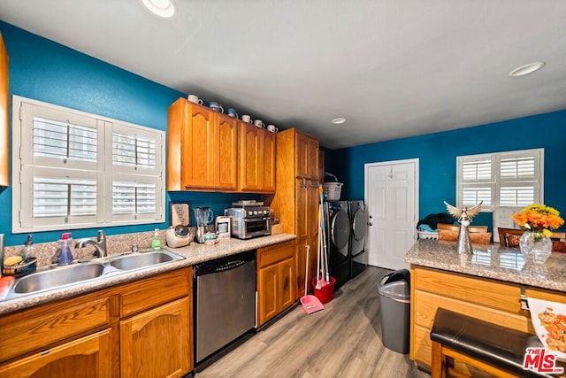 kitchen with light wood-type flooring, stainless steel dishwasher, washer and clothes dryer, and sink