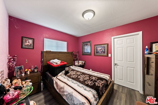 bedroom with dark hardwood / wood-style flooring and a textured ceiling