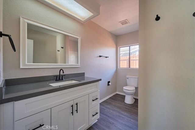 bathroom featuring wood-type flooring, toilet, and vanity