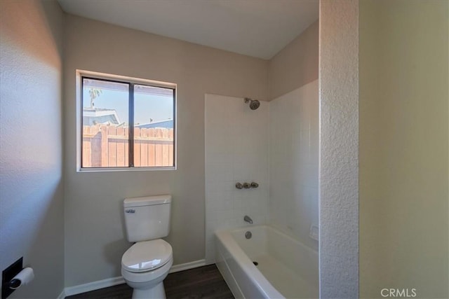 bathroom with tiled shower / bath combo, wood-type flooring, and toilet