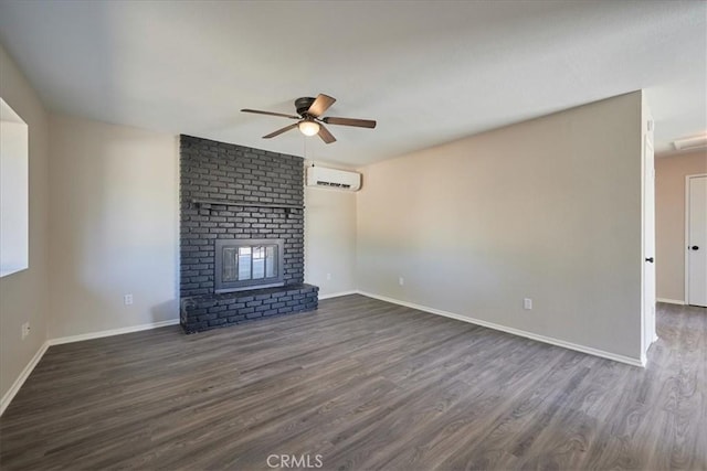 unfurnished living room with ceiling fan, dark wood-type flooring, a wall unit AC, and a brick fireplace