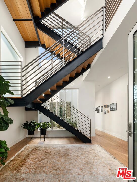 stairs with hardwood / wood-style floors, wooden ceiling, and a high ceiling