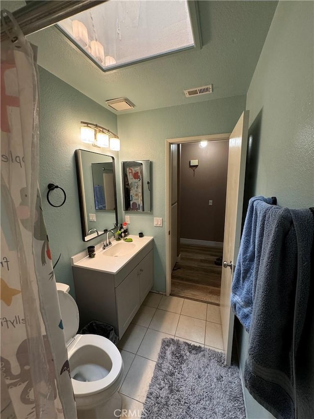 bathroom featuring tile patterned floors, vanity, a textured ceiling, and toilet