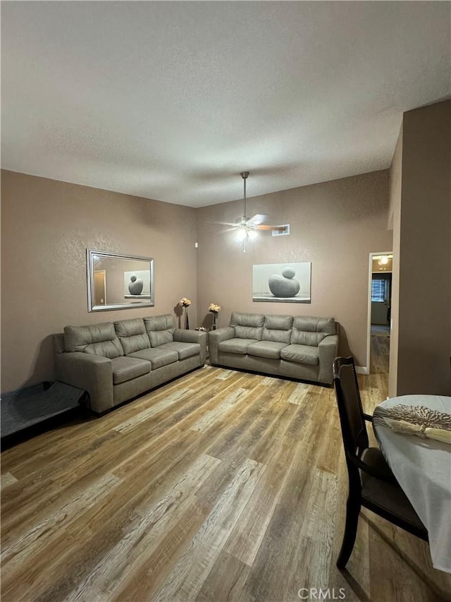 living room featuring ceiling fan, a textured ceiling, and hardwood / wood-style flooring