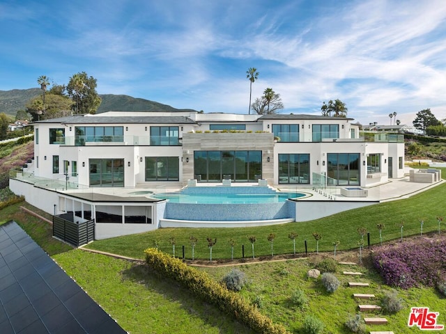 back of property with a mountain view, a yard, and a patio