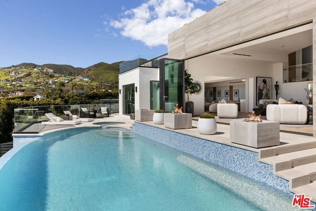 view of pool with an in ground hot tub, a mountain view, and a patio area