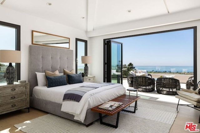 bedroom with hardwood / wood-style flooring, multiple windows, and a water view