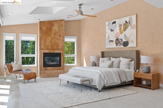 bedroom featuring ceiling fan, lofted ceiling, light carpet, and a large fireplace