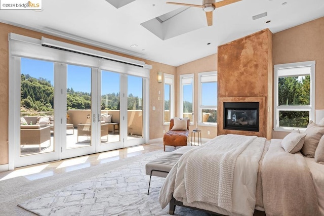 bedroom featuring ceiling fan, french doors, access to exterior, a large fireplace, and vaulted ceiling