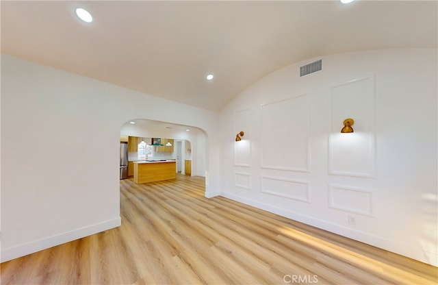 empty room with light hardwood / wood-style floors and lofted ceiling